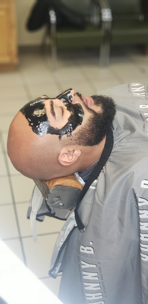 The charcoal face mask service — activated black mask mid-treatment.